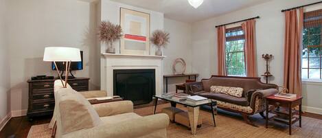 A living room with a fireplace, sofa, armchairs, a coffee table, and a television.