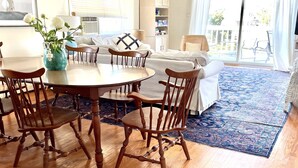 A dining area with a wooden table and chairs, a vase with flowers, and a ceiling fan.