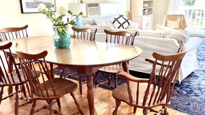 A dining area with a round wooden table and six chairs, a vase with flowers, and a ceiling fan.