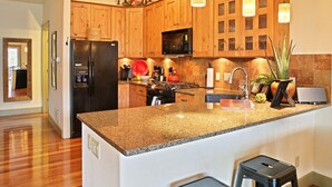 Eine moderne Küche mit Holzausstattung, Granit Arbeitsplatten, einem schwarzen Kühlschrank, einer Mikrowelle und einem Spülbecken.