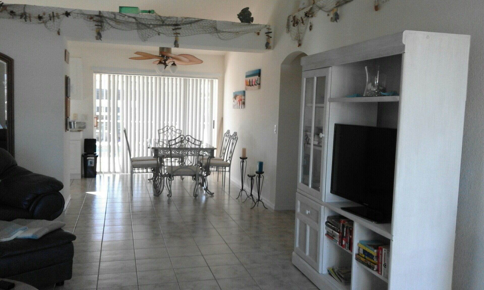 A living room with a dining area, a television on a cabinet, and a ceiling fan.