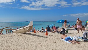 A beach with a boat, umbrellas, and people relaxing. - "Cozy Cottage"  Your lovely Home , direct gulf access  in best and quit SW Cape  (Cape Coral)