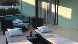 A sunlit outdoor lounge area with two reclining chairs, a small table with a bottle and glasses, and a black planter. - "Cozy Cottage"  Your lovely Home , direct gulf access  in best and quit SW Cape  (Cape Coral)