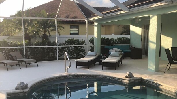 An outdoor swimming pool with lounge chairs and a covered seating area. - "Cozy Cottage"  Your lovely Home , direct gulf access  in best and quit SW Cape  (Cape Coral)