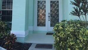 A house with a light green exterior, a white door with glass panels, and a small porch area. - "Cozy Cottage"  Your lovely Home , direct gulf access  in best and quit SW Cape  (Cape Coral)