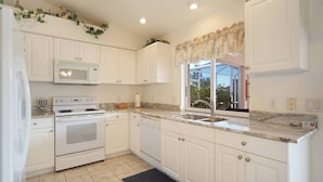 A kitchen with white cabinets, a microwave, stove, and sink. - "Cozy Cottage"  Your lovely Home , direct gulf access  in best and quit SW Cape  (Cape Coral)