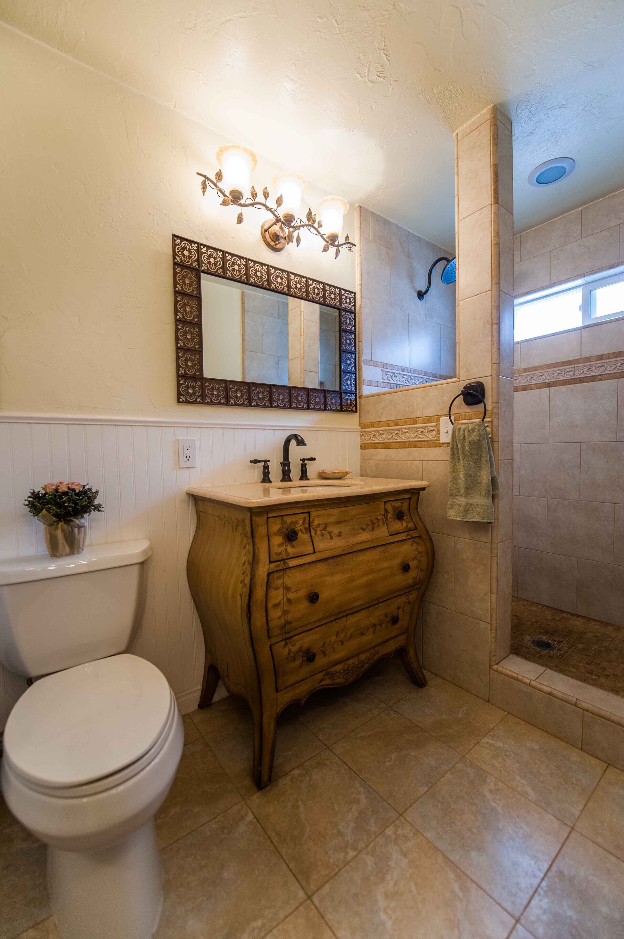 A bathroom with a toilet, wooden vanity, and a shower area.