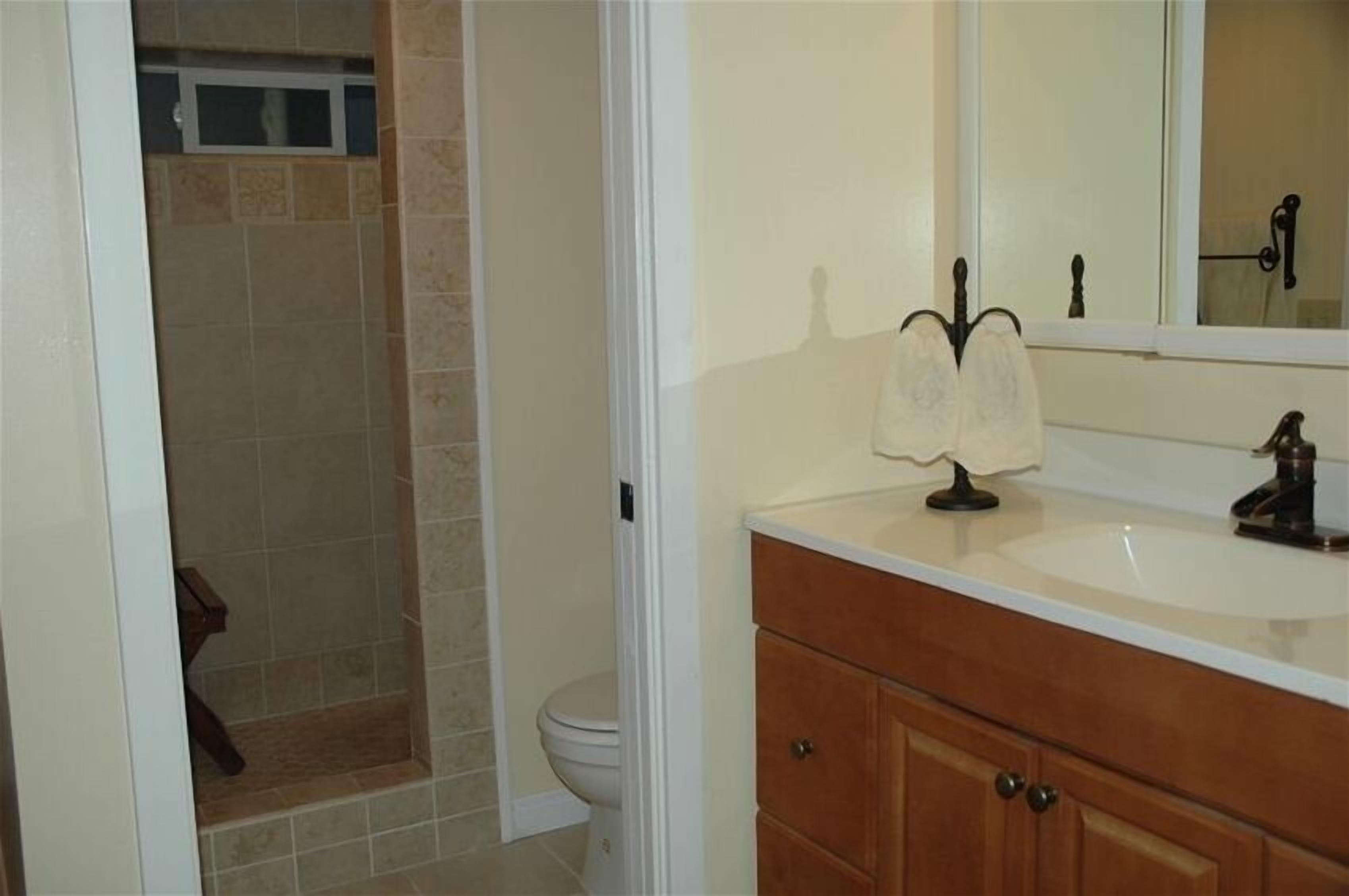 A bathroom with a white sink, wooden vanity, and a mirror.
