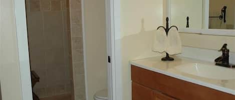 A bathroom with a white sink, wooden vanity, and a mirror.