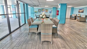 Une pièce avec un mur en verre, des meubles en osier et une table sur laquelle est posé un vase.