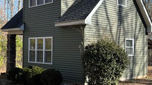 A two-story house with a stone chimney, a small front yard, and a leaf-covered ground. - Solar powered cottage at lake, with dock, on private 300 acre timber preserve (Clarksville)