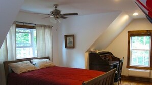 A bedroom with a bed, a ceiling fan, and a desk with a chair. - Solar powered cottage at lake, with dock, on private 300 acre timber preserve (Clarksville)