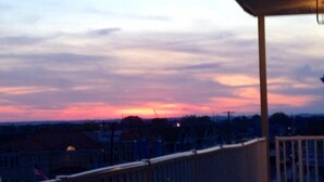 Ein Balkon mit Blick auf einen Sonnenuntergang über einem Wohngebiet.