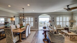A spacious living room with a dining area, large windows, and a ceiling fan. - Private Beach Access Gulf-View Penthouse 3BR/3BA Near Seaside (Seagrove Beach)