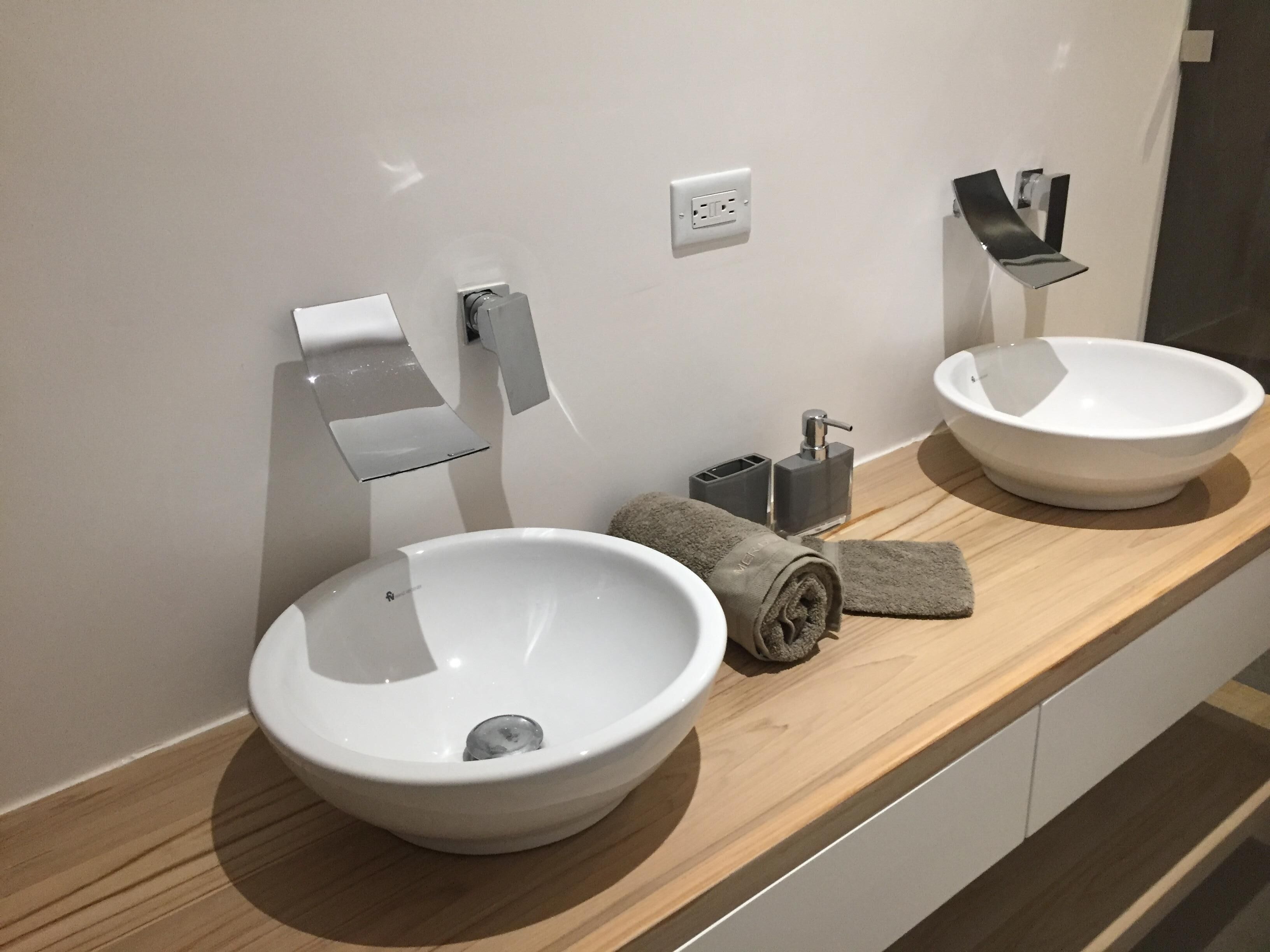 A bathroom with two white ceramic sinks, a towel, a soap dispenser, and a mirror.