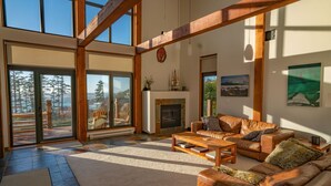 Ein geräumiges Wohnzimmer mit Kamin, Ledersofas und großen Fenstern mit Blick ins Freie.
