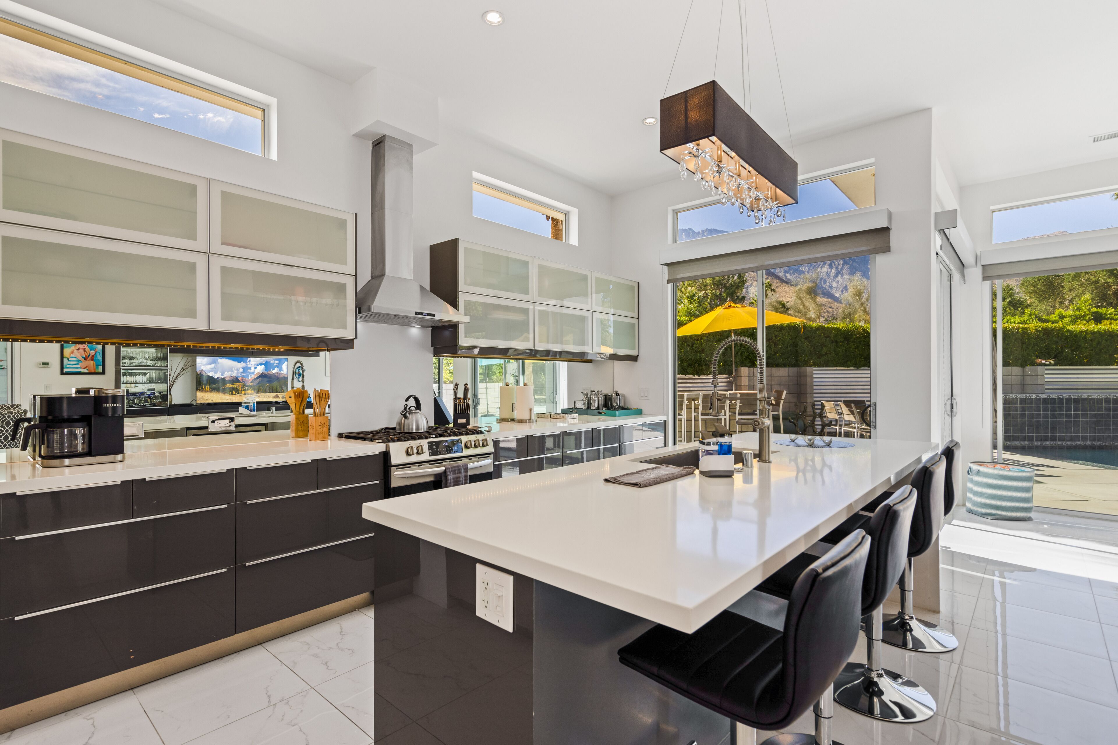 A modern kitchen with a large island, black and white cabinetry, and a view of the outdoors.