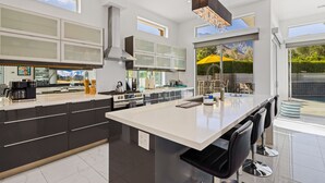 A modern kitchen with a large island, black and white cabinetry, and a view of the outdoors. - Spring into Palm Springs and escape winter! (Palm Springs)