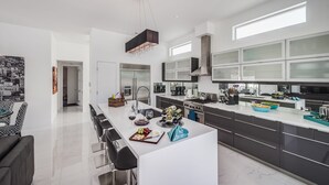 A modern kitchen with a central island, stainless steel appliances, and a large window. - Spring into Palm Springs and escape winter! (Palm Springs)