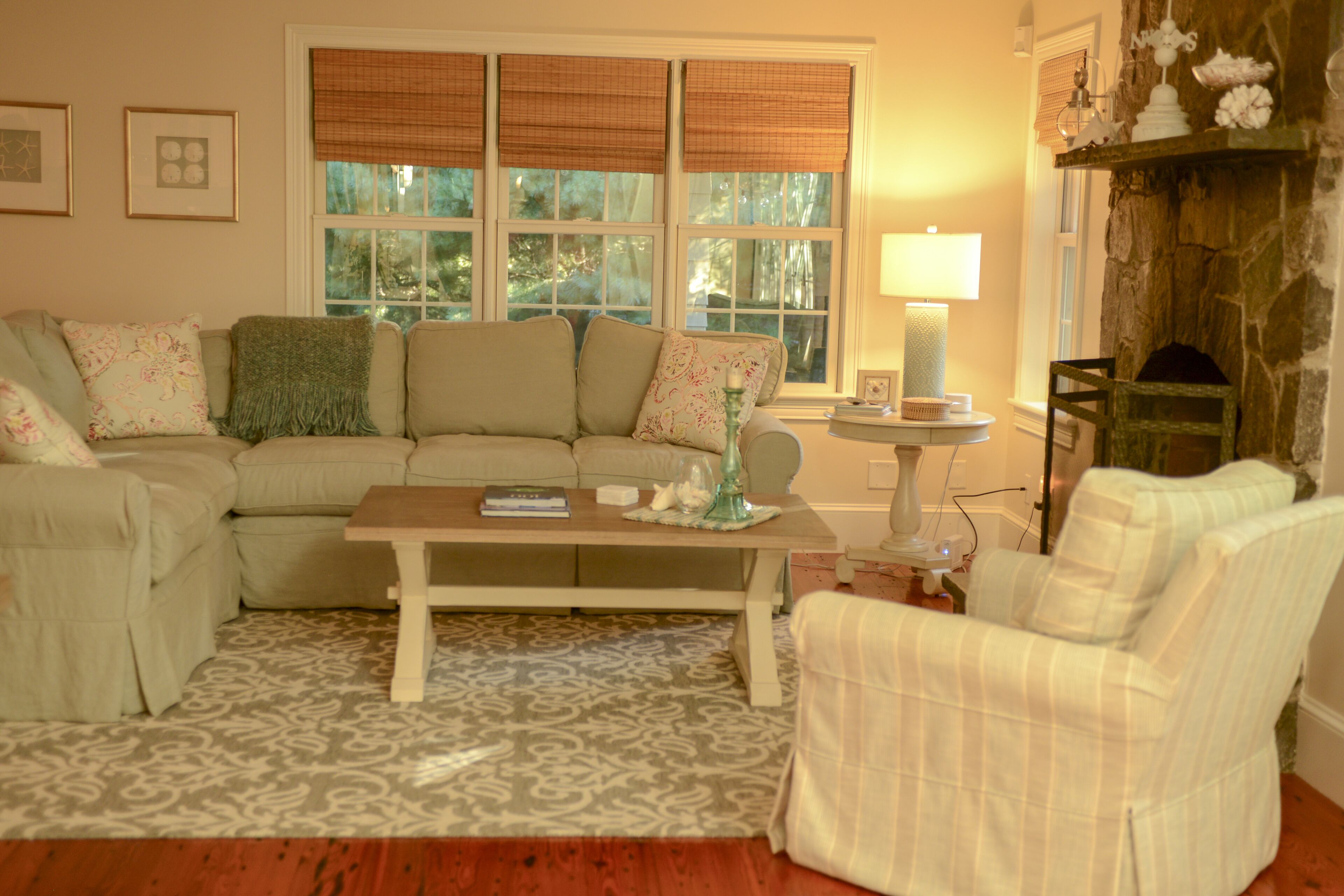 A cozy living room with a sectional sofa, a patterned rug, a small table, and a fireplace.