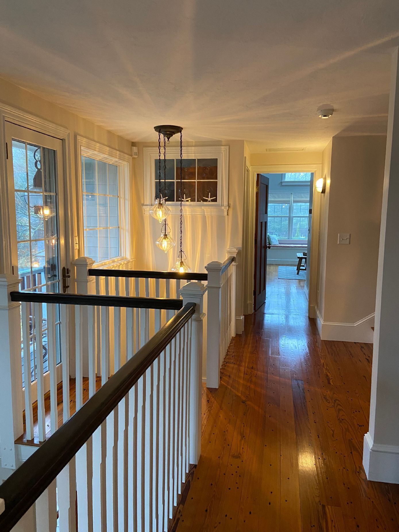 A wooden-floored hallway with white railings and a staircase.
