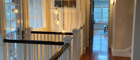 A wooden-floored hallway with white railings and a staircase.