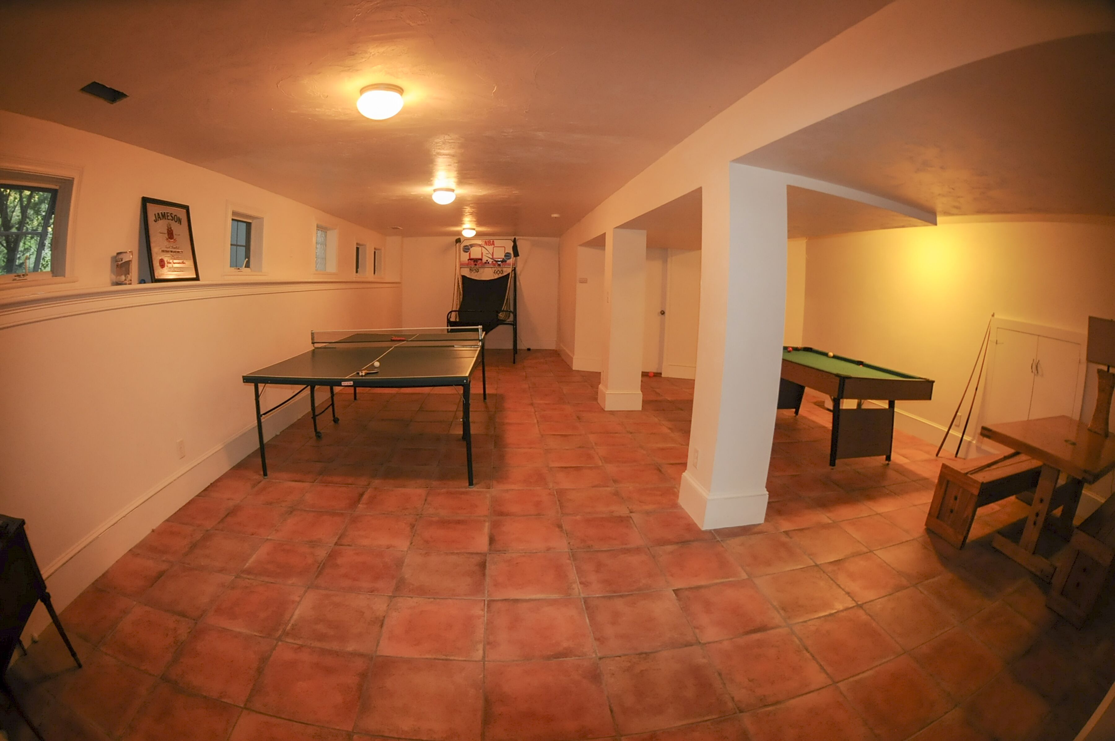 En rummelig stue med et ping-pong bord, et billardbord og et poolbord.