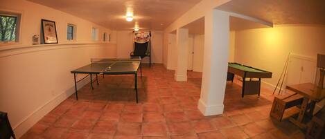 En rummelig stue med et ping-pong bord, et billardbord og et poolbord.