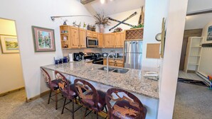 A kitchen with granite countertops, wooden cabinets, a stainless steel refrigerator, and a built-in microwave.