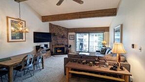 A living room with a fireplace, a television, a dining area, and a sofa.