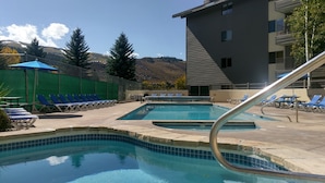A pool area with multiple lounge chairs and a pool with a tiled edge.