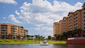 Ein Hotel mit mehreren Stockwerken, einem Schwimmbad und einer Schwanstatue im Wasser.