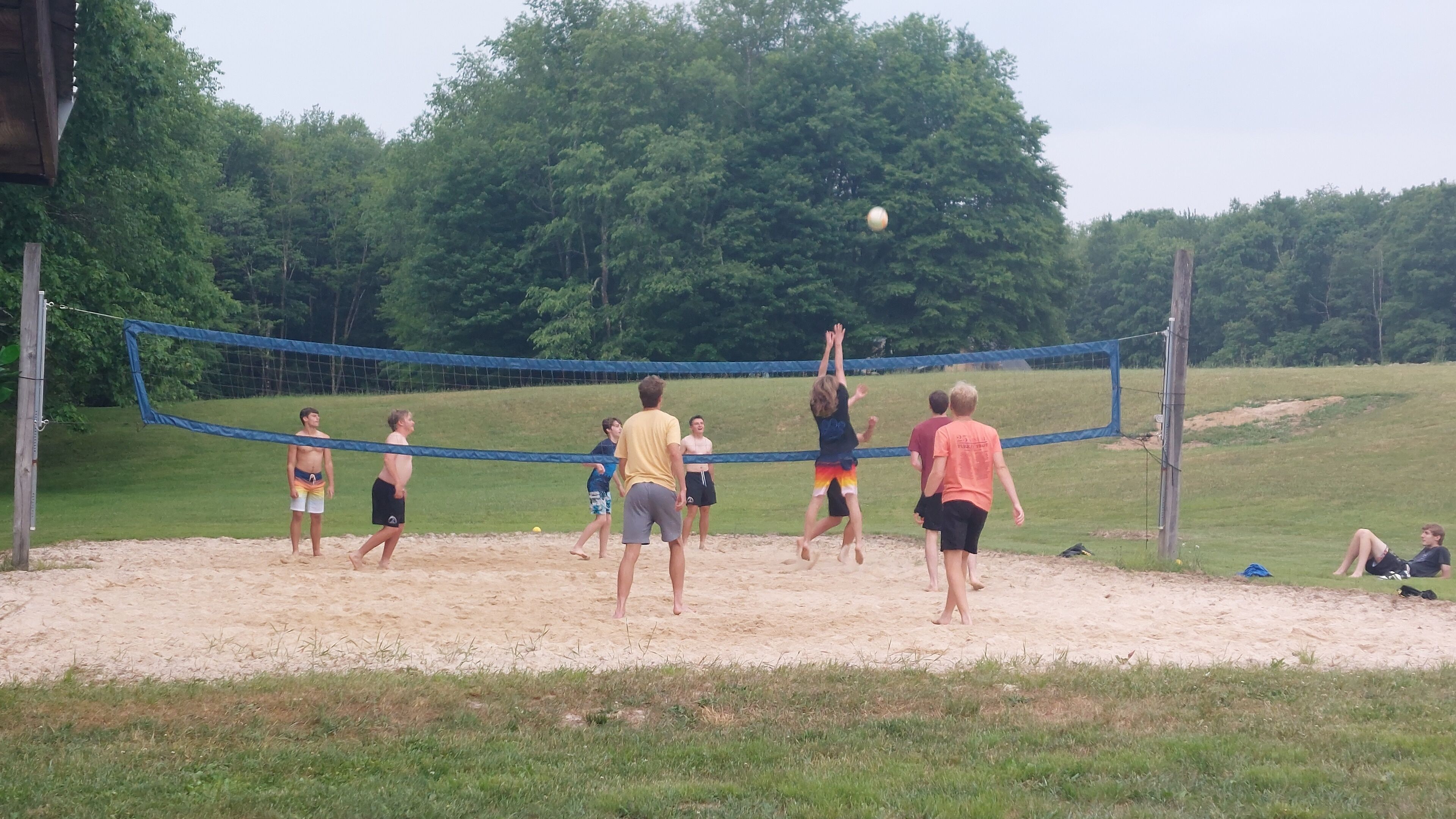 Un grupo de personas jugando voleibol en una cancha de arena con una red.