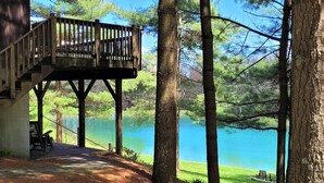 A wooden deck with a railing overlooking a lake, surrounded by trees. - Minutes from Deep Creek Lake, Located on 24-acre farm with private 1-acre lake (Accident)