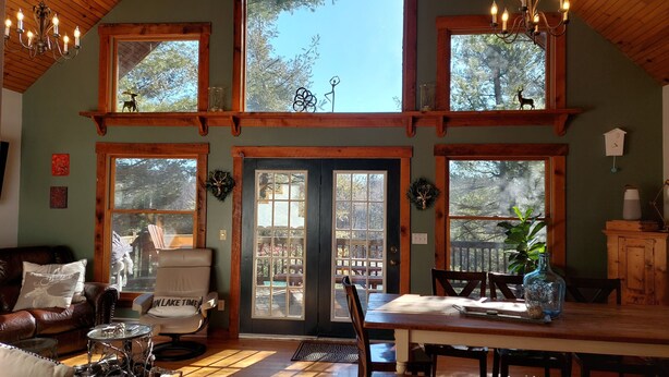 A cozy cabin interior with a leather couch, a chair, a dining table, and multiple windows offering views of the outdoors. - Minutes from Deep Creek Lake, Located on 24-acre farm with private 1-acre lake (Accident)