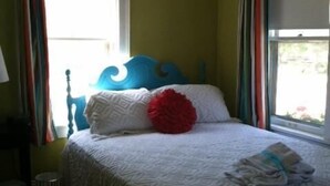 A bedroom with a bed, curtains, and a window.