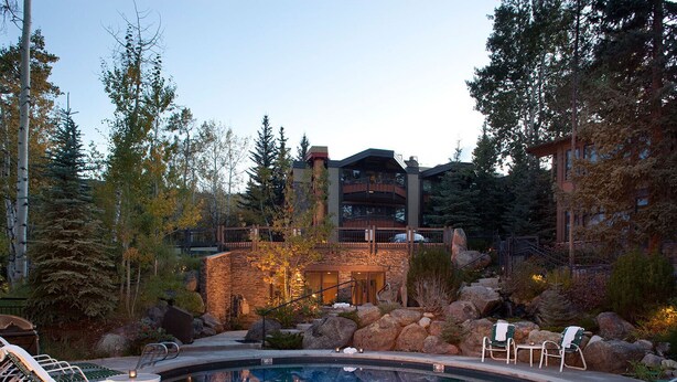 A serene indoor pool area with lounge chairs, a stone wall, and a view of a multi-story building. - Sonnenblick 6: Ski In, Pool, Hot Tub, In the Heart of Snowmass, No Car Needed  (Snowmass Village)