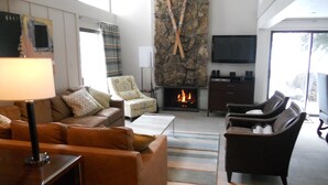 A modern living room with a fireplace, leather sofas, a television, and a stone accent wall.