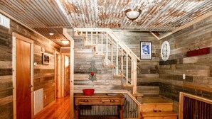 Un interior rústico de madera con una escalera, un banco y un letrero en la pared.