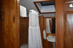 A wooden bathroom with a shower curtain, a sink, and a mirror. - The Cornerstone Cabin - Mount Rainier (Ashford)
