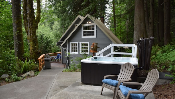 A house with a hot tub, two Adirondack chairs, and a wooden deck. - The Cornerstone Cabin - Mount Rainier (Ashford)
