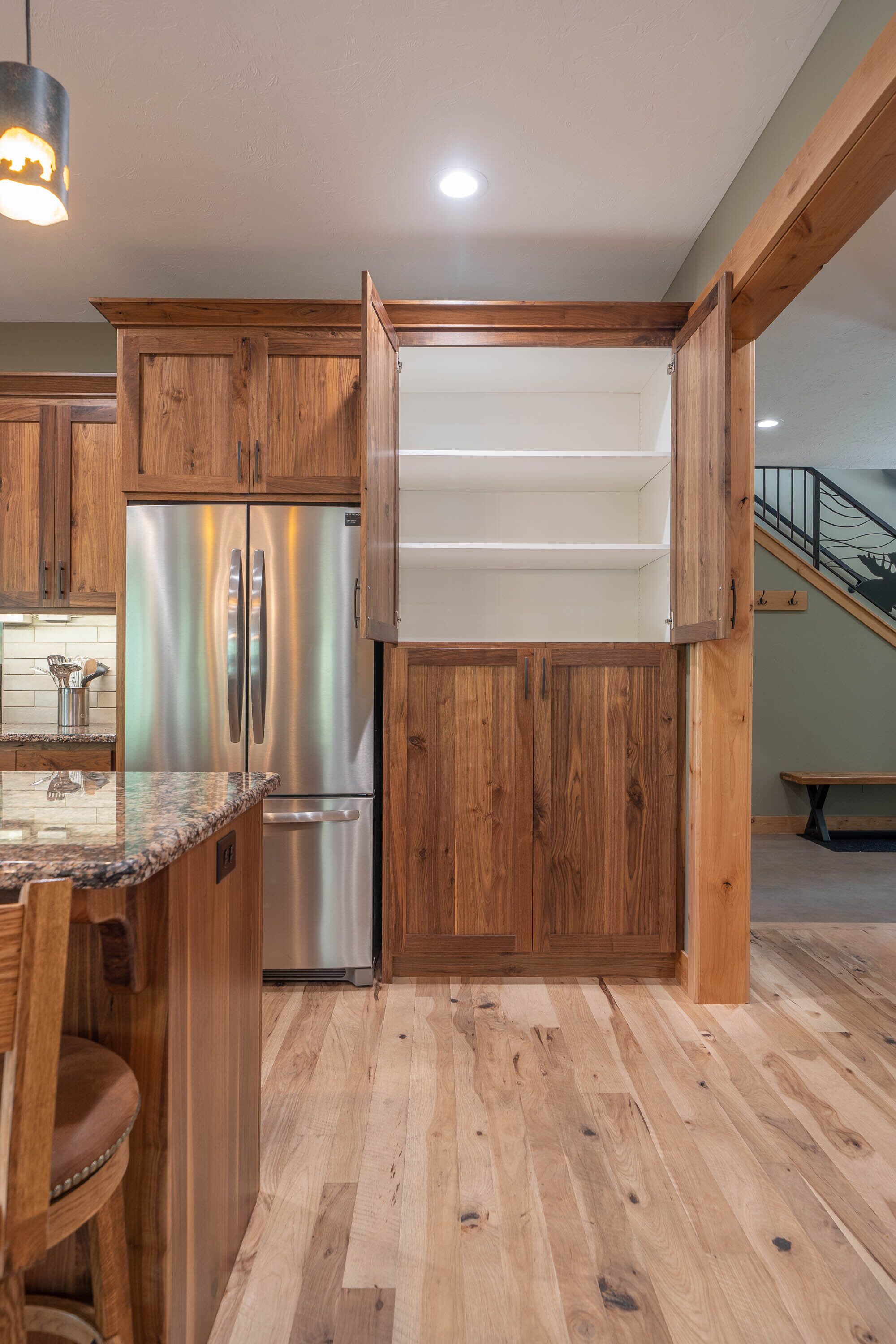 A kitchen with wooden cabinets, a stainless steel refrigerator, and a granite countertop.