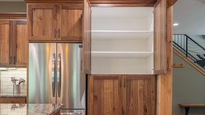 Une cuisine avec des meubles en bois, un réfrigérateur en acier inoxydable et un plan de travail en granit.