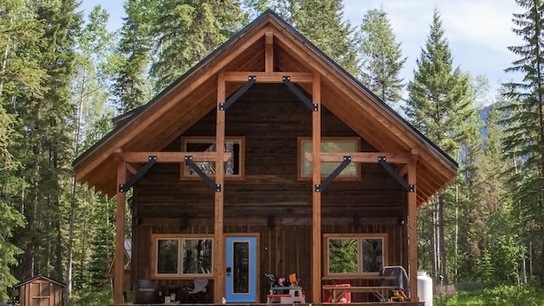 A wooden cabin with a porch, large windows, and a door.