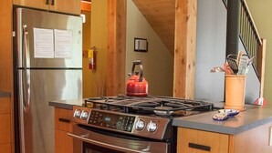 A compact kitchen with a stainless steel refrigerator, a gas stove, and wooden cabinets.
