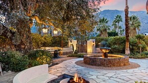 A landscaped outdoor area with a fire pit, stone pathways, and a view of a mountain.