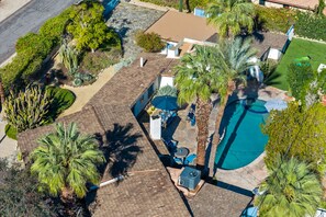Vista aérea de una propiedad residencial con piscina, muebles de patio y diversas plantas.