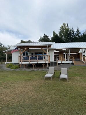 Une maison moderne dotée d’un porche couvert, d’un drapeau et d’une pelouse.