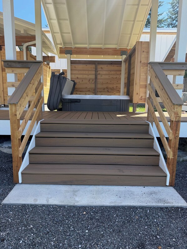 A wooden deck with a ramp leading to a covered seating area.