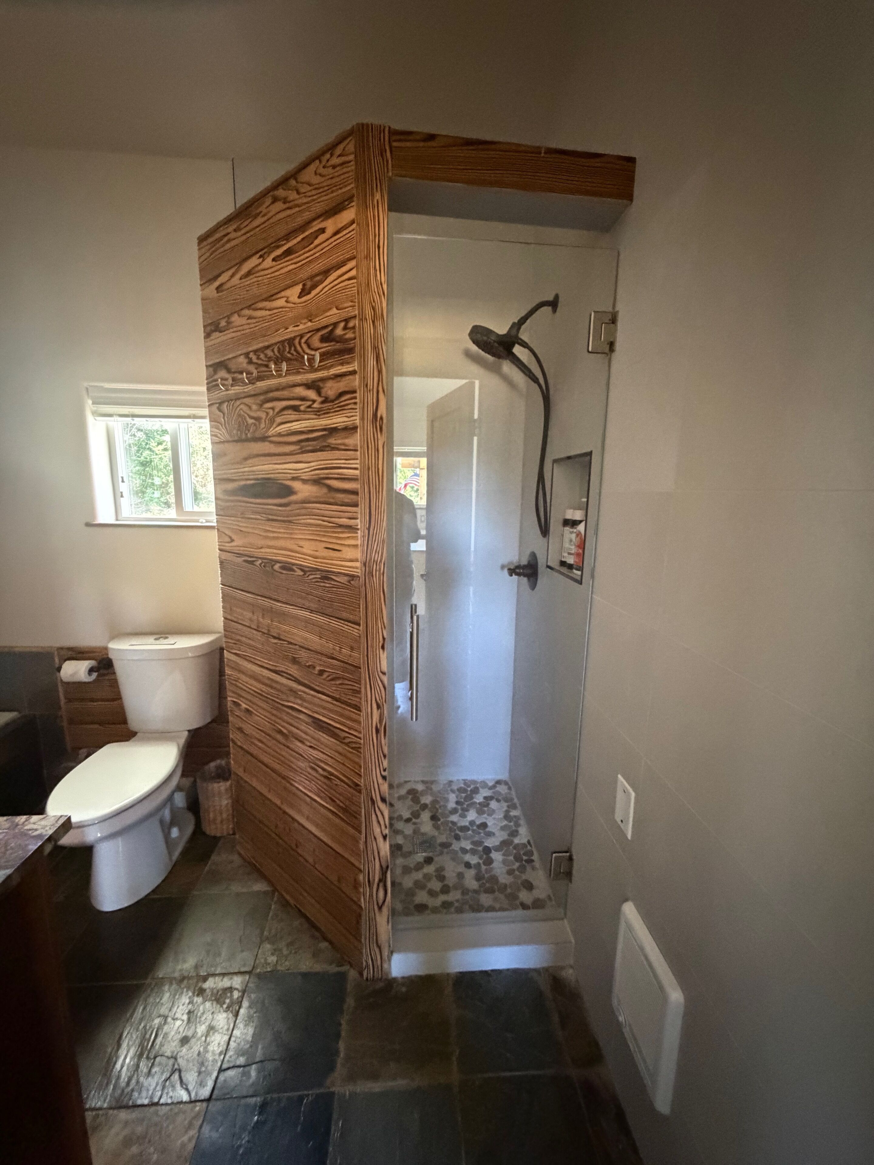 Une salle de bain avec une douche, des toilettes et une fenêtre.